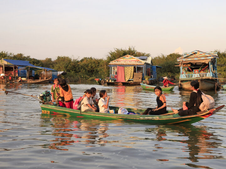 Children returning from school by boat in the floating village on Tonle Sap Lake before sunset in Siem Reap, Cambodia